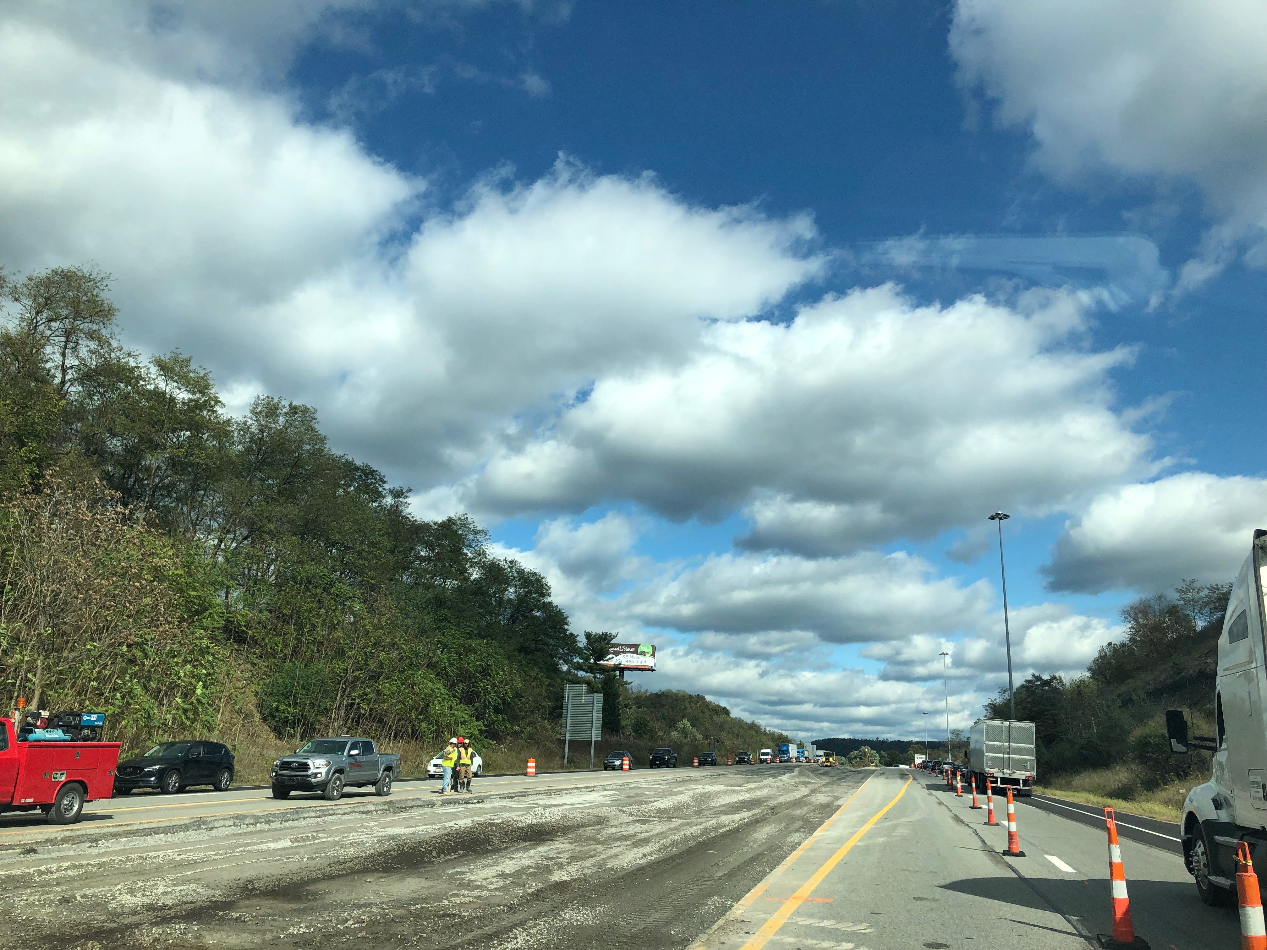 Interstate 70 construction zone in Wheeling featuring milled pavement and traffic barrels under a cloudy sky.