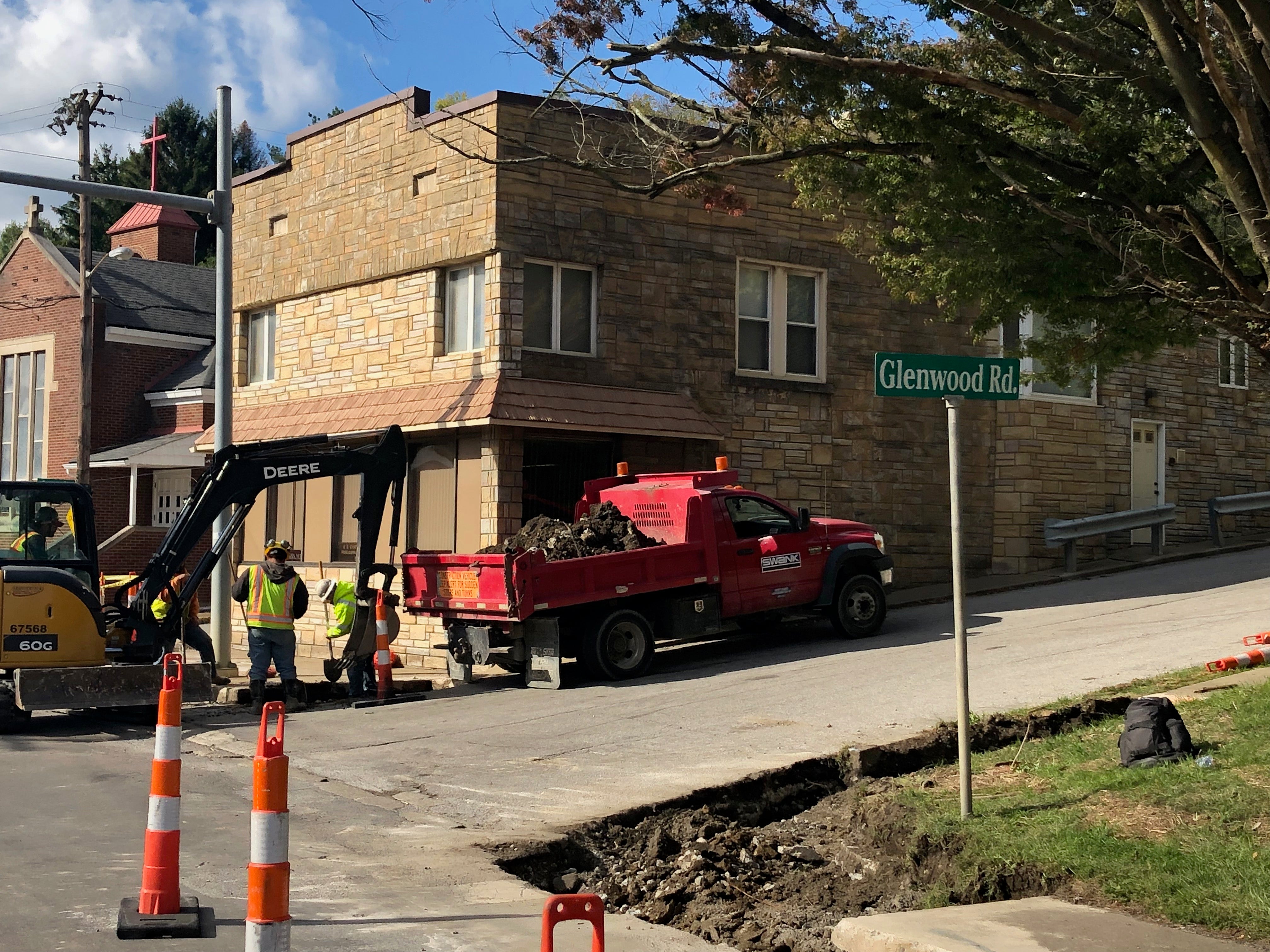 Construction crew and a red dump truck performing road repairs at the intersection of Glenwood Road in Wheeling.