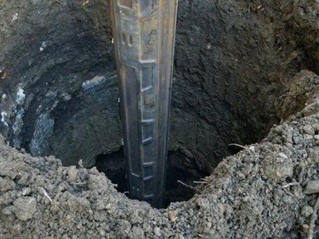 Close-up of a metal structural pile being placed into a deep drilled hole for a bridge foundation as part of the I-70 rehabilitation project.