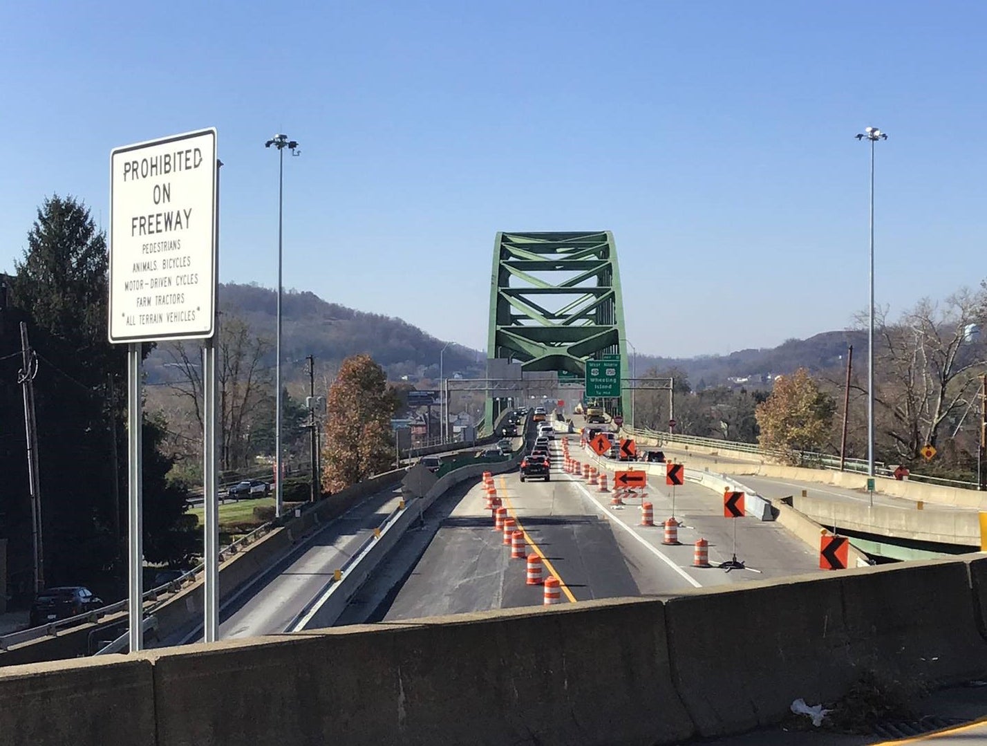 View of the Fort Henry Bridge in Wheeling, West Virginia, with traffic barrels and construction signage on the I-70 approach.