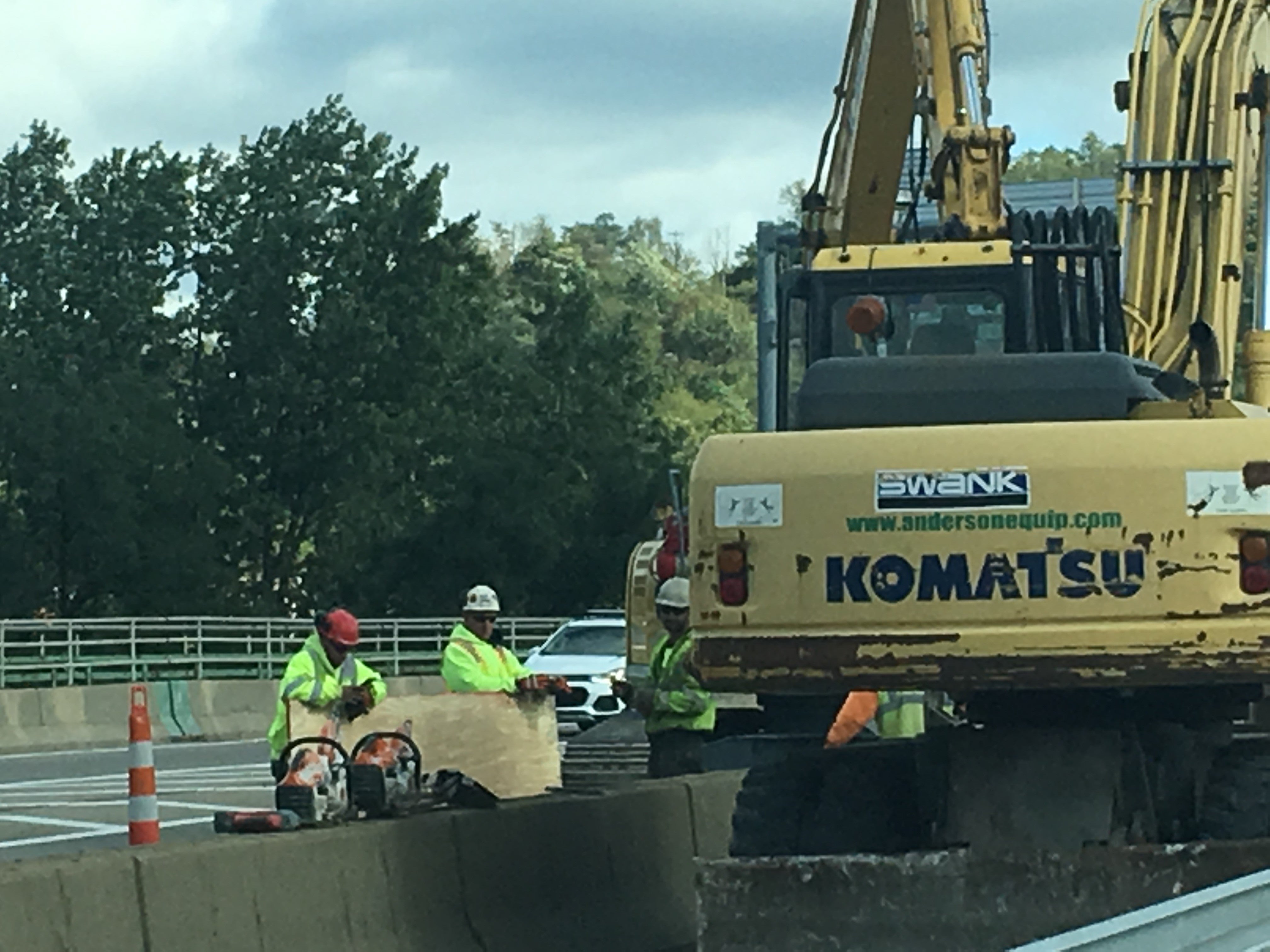 Construction workers and a yellow excavator performing bridge rehabilitation work on the I-70 corridor in Wheeling
