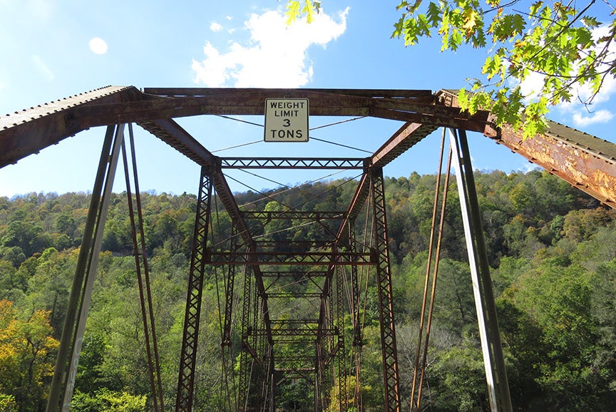 Rusty iron truss structure of Bull Run Bridge with a three-ton weight limit sign.