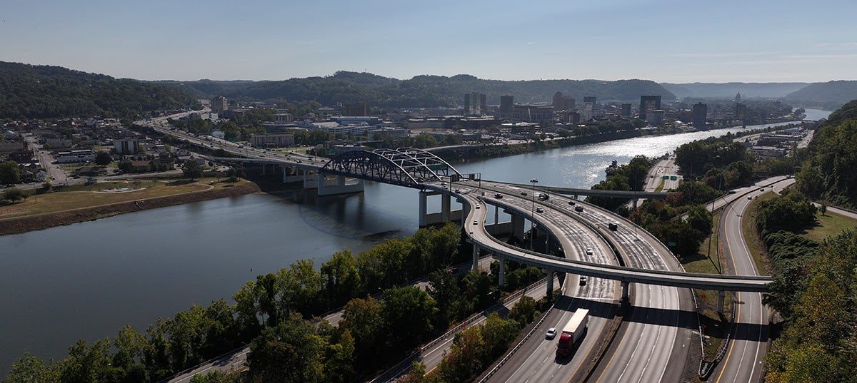 Aerial view of the Fort Hill Bridge and its complex highway interchange over a river in Charleston.